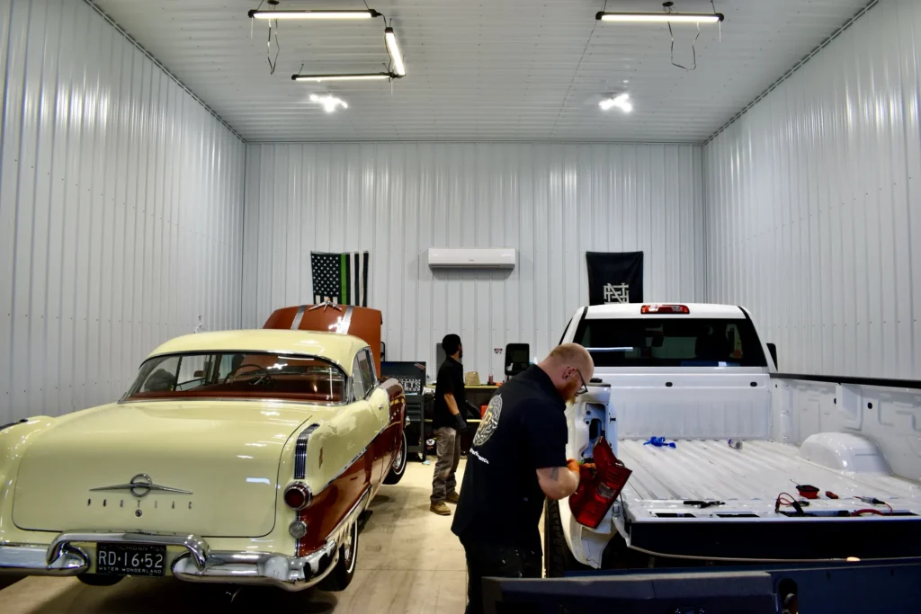 Classic two-tone Pontiac and a white pickup inside the Elevated Performance shop
